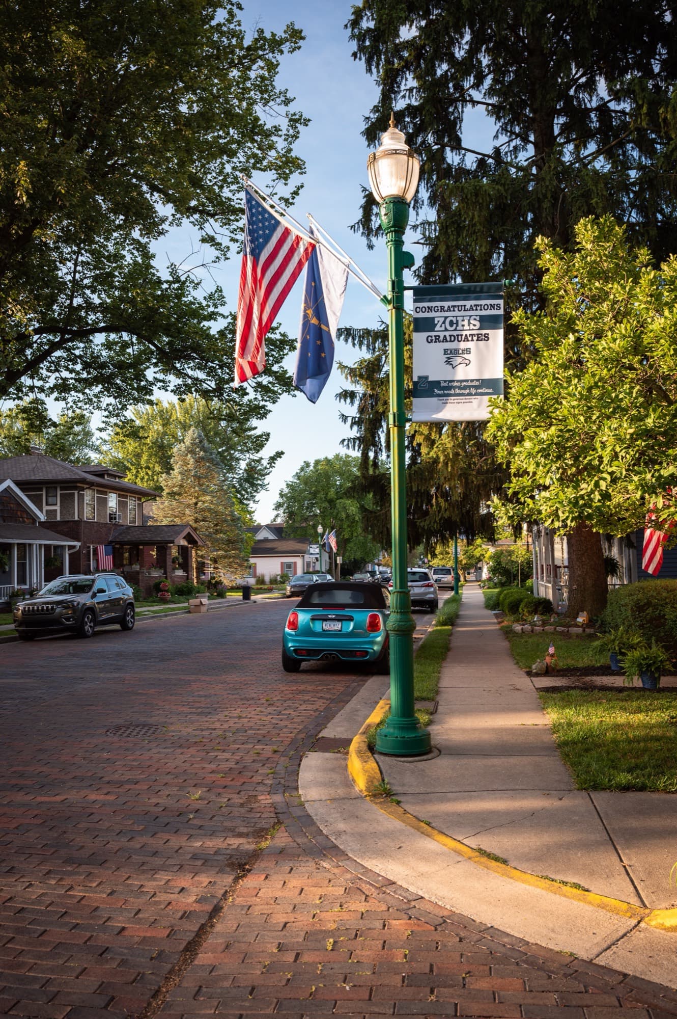 A tree-lined street in Zionsville, Indiana, with American and Indiana flags on the lamp posts